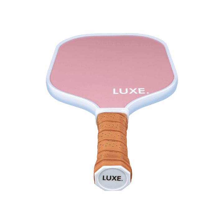 Pink pickleball paddle with brown handle on a transparent background.