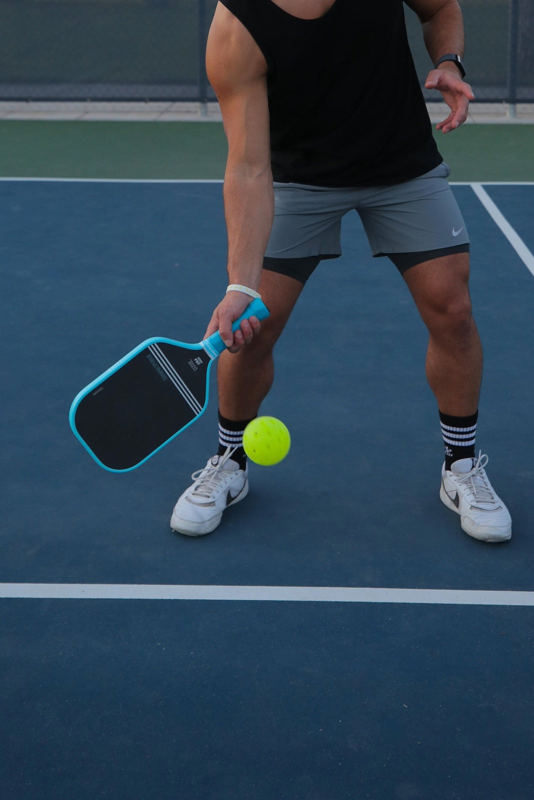 Person holding a paddle and a ball on a tennis court.