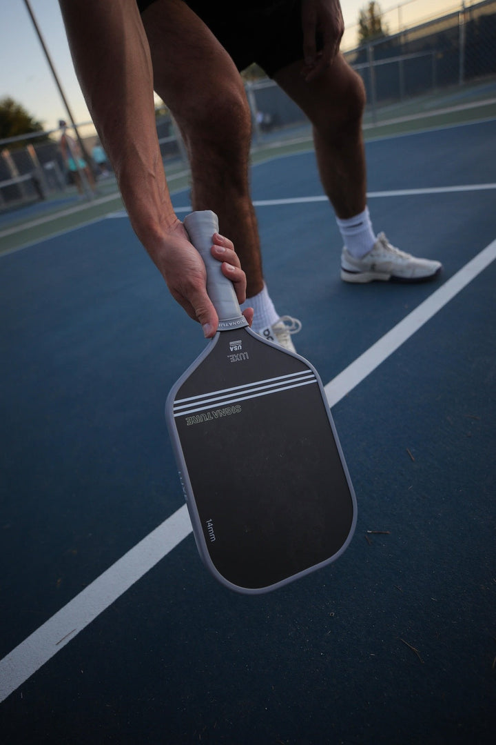 Person holding a pickleball paddle on a court.