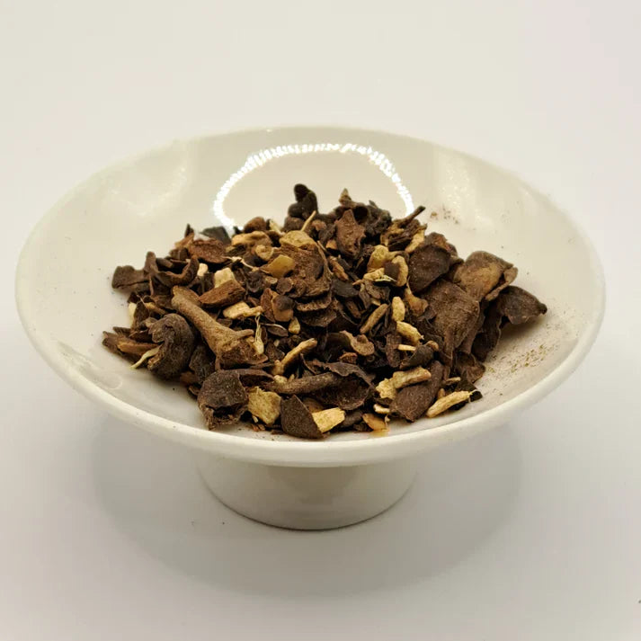 White bowl filled with dried herbs on a white background.