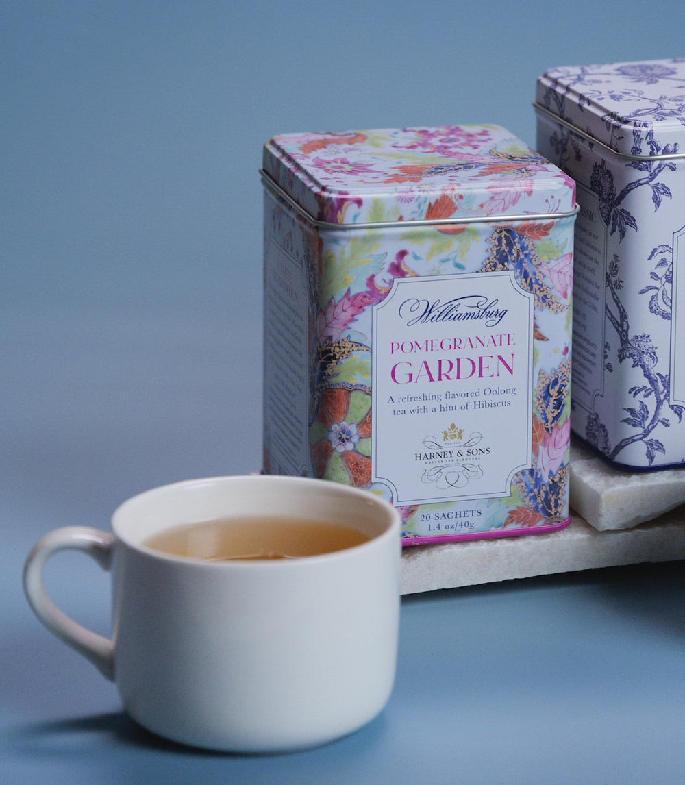 Teacup with floral tea tins on a blue background.