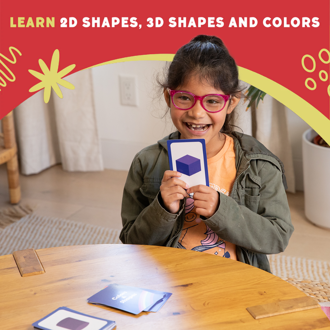 Child holding a card with a shape on it, learning 2D and 3D shapes and colors.
