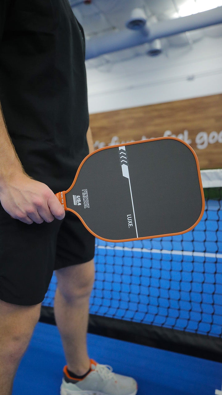 Person holding a pickleball paddle on a court.