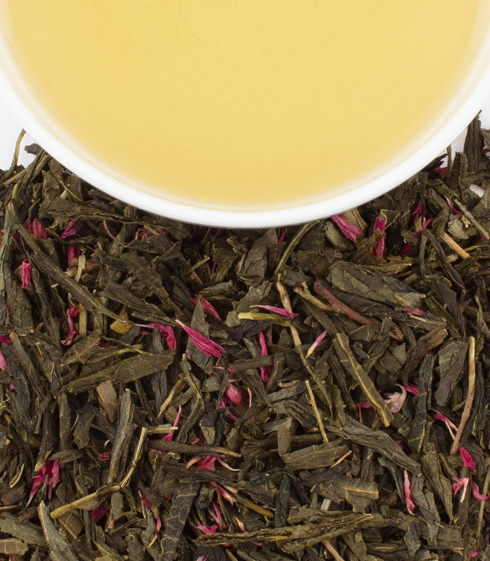 Tea leaves with a cup of tea in the background.