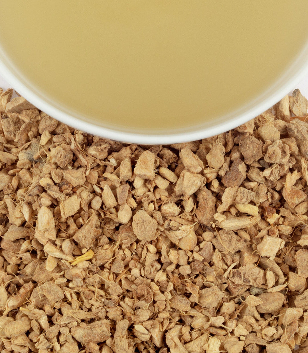 Close-up of dried herbs with a cup of tea in the background