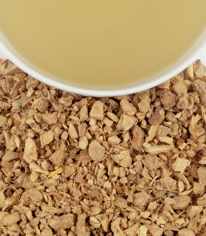 Close-up of dried herbs with a cup of tea in the background