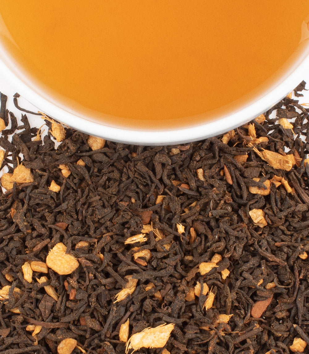 Close-up of tea leaves with a cup of tea in the background