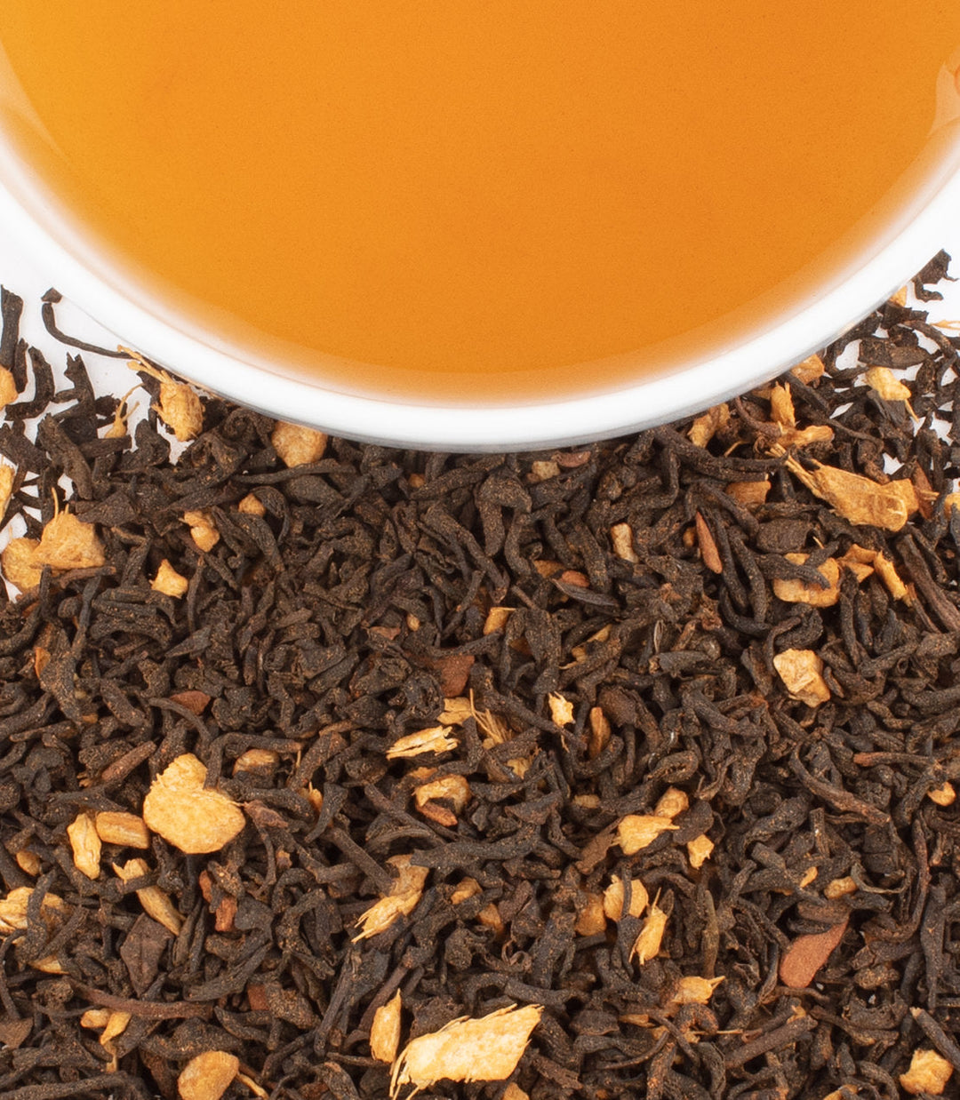 Close-up of tea leaves with a cup of tea in the background
