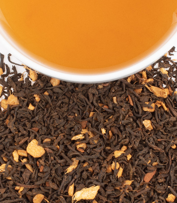 Close-up of tea leaves with a cup of tea in the background
