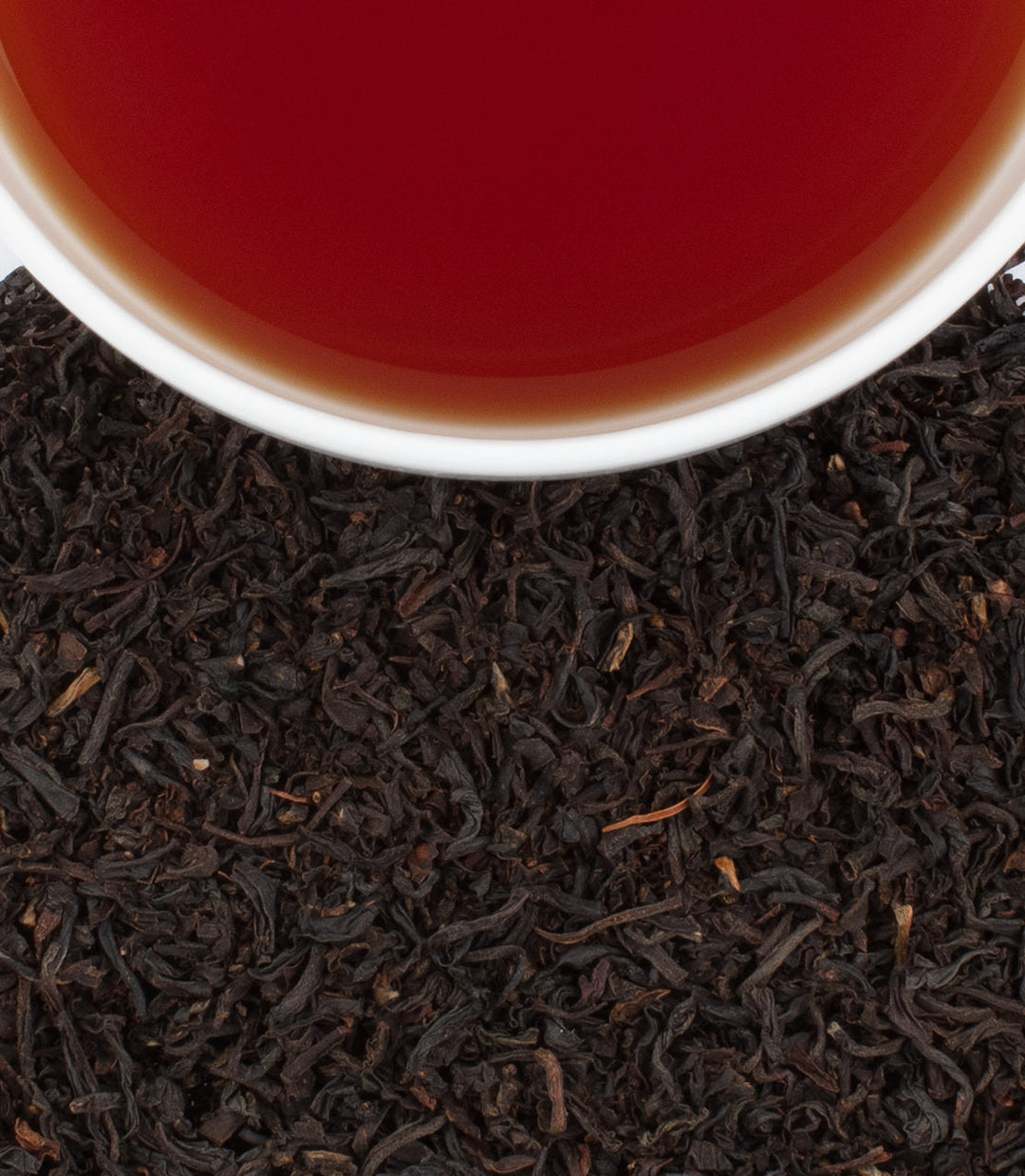 Close-up of tea leaves with a cup of tea in the background.