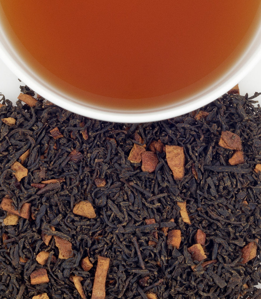Close-up of tea leaves with a cup of tea in the background.
