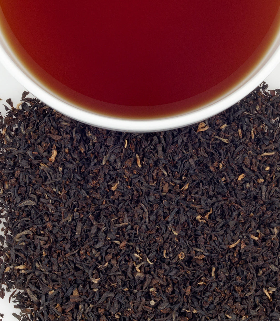 Close-up of tea leaves with a cup of tea in the background