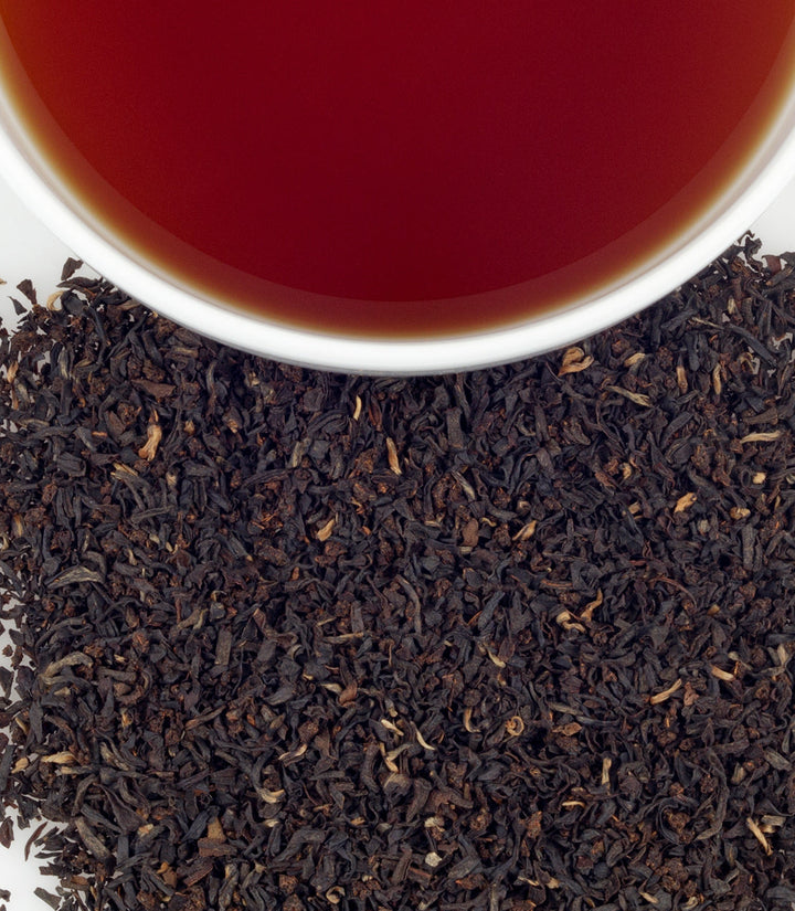 Close-up of tea leaves with a cup of tea in the background