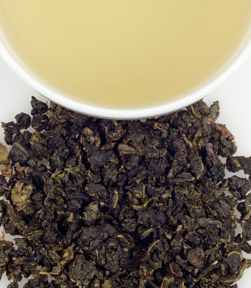 Oolong tea leaves with a cup of tea in the background