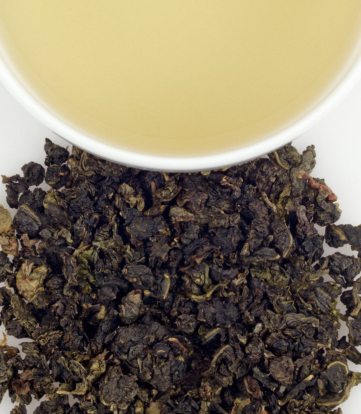 Oolong tea leaves with a cup of tea in the background
