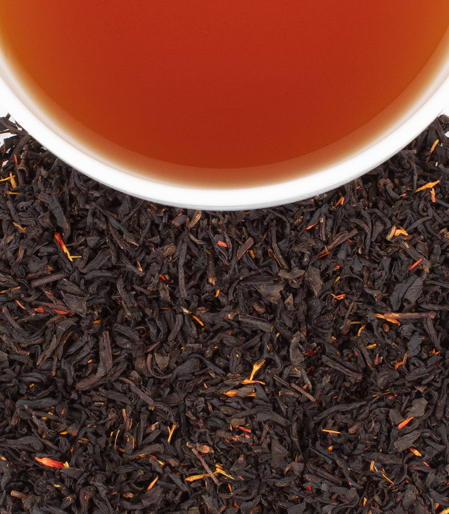 Close-up of tea leaves with a cup of tea in the background