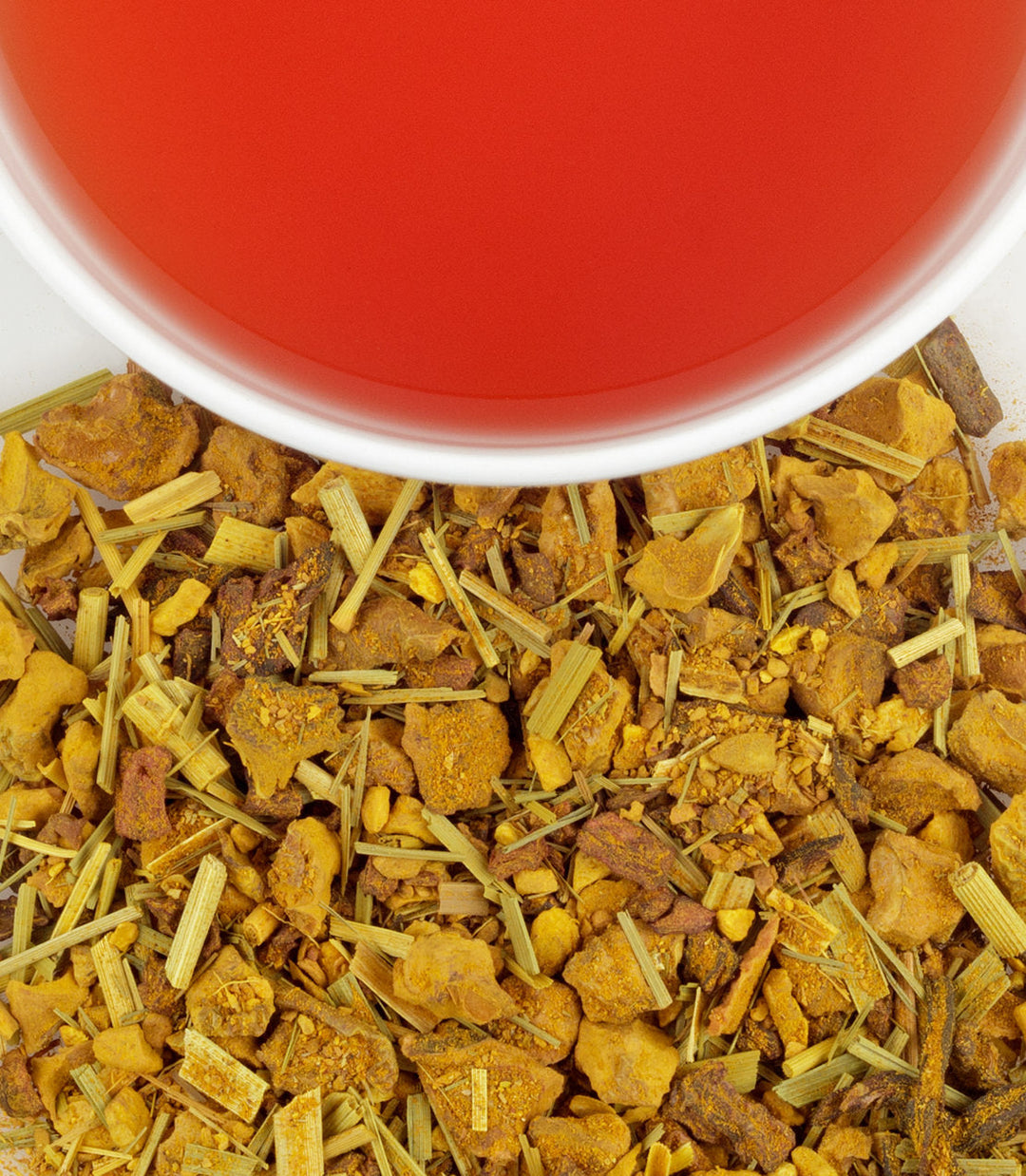 Herbal tea leaves with a cup of red tea in the background.