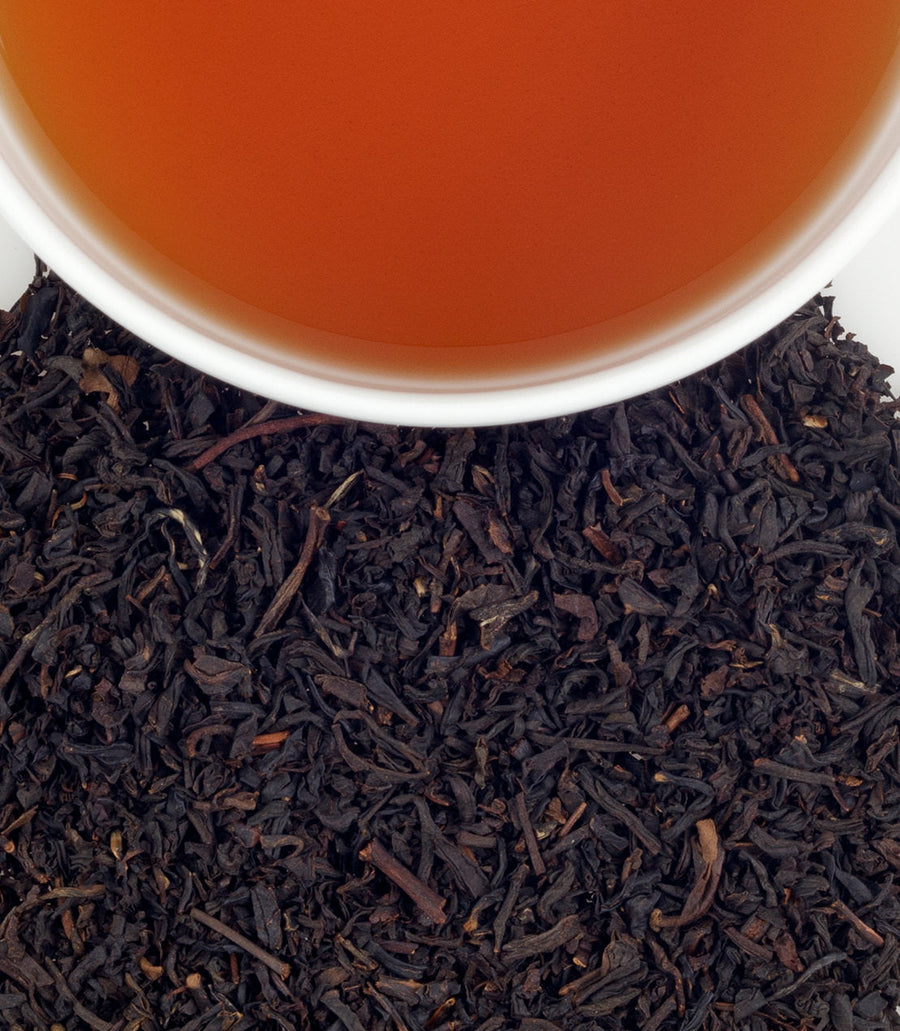 Close-up of tea leaves with a cup of tea in the background.
