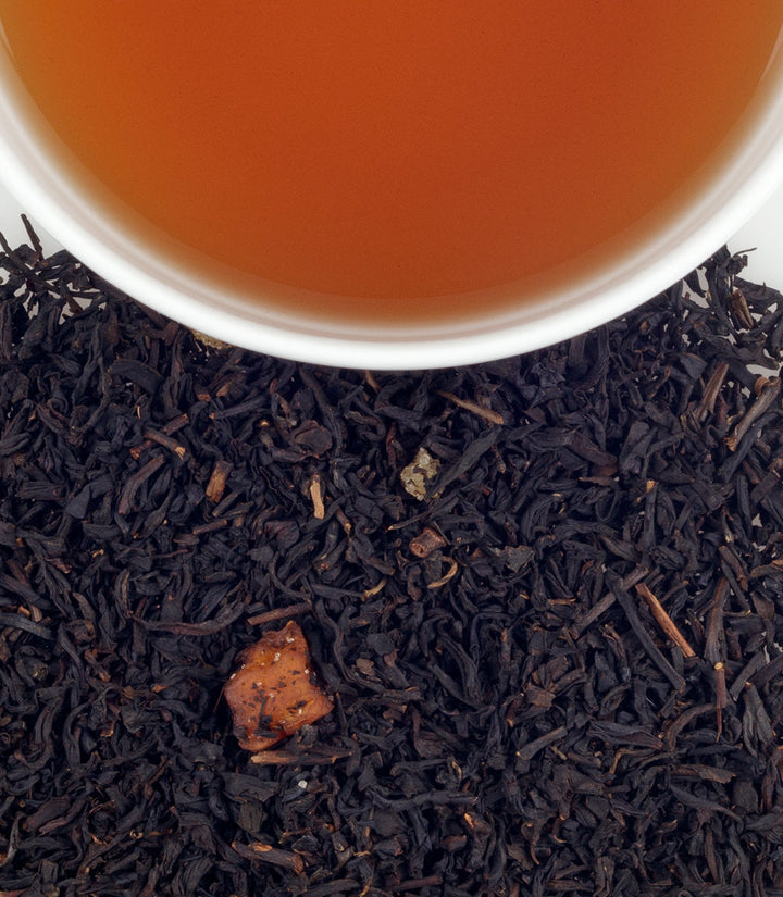 Close-up of tea leaves with a cup of tea on a white background