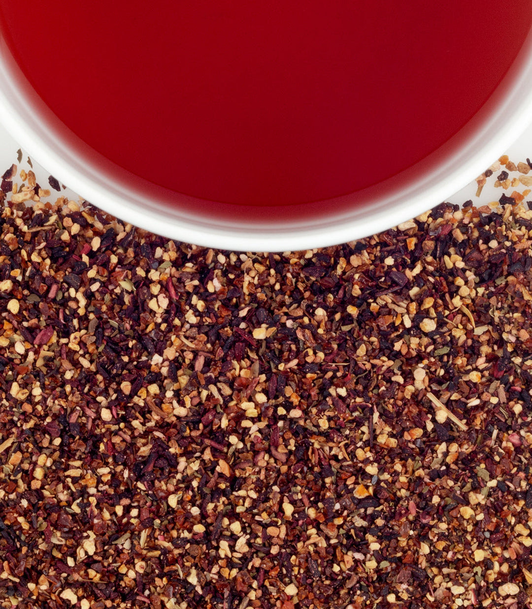Close-up of dried tea leaves with a cup of red tea in the background