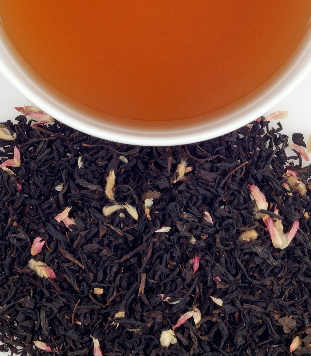 Tea leaves with a cup of tea in the background.