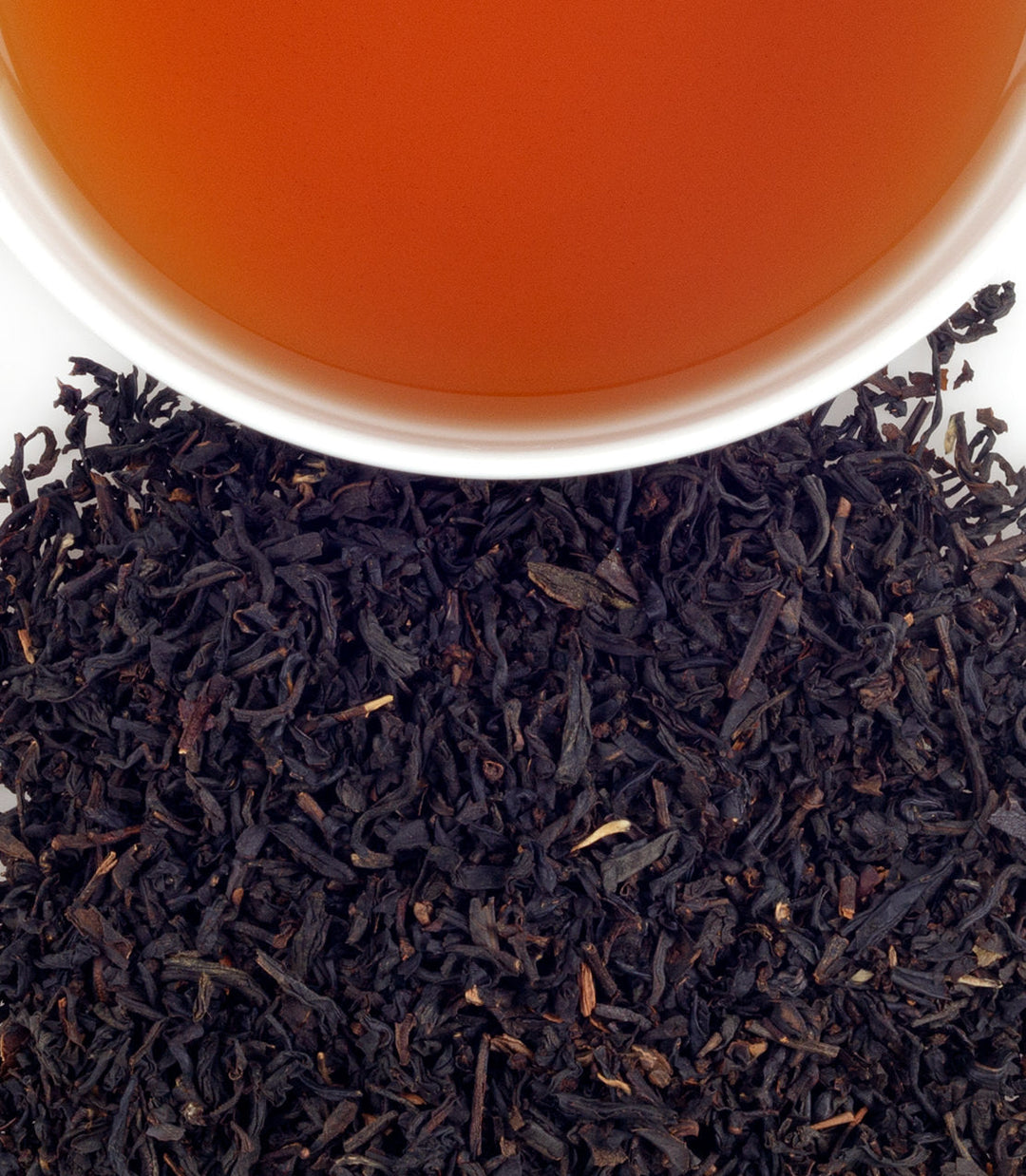 Close-up of tea leaves with a cup of tea in the background