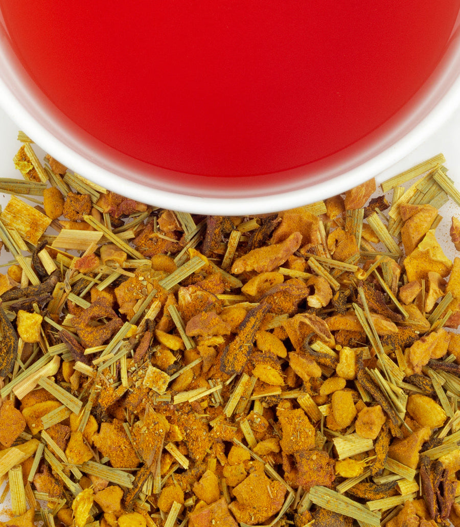 Herbal tea leaves with a cup of red tea in the background.