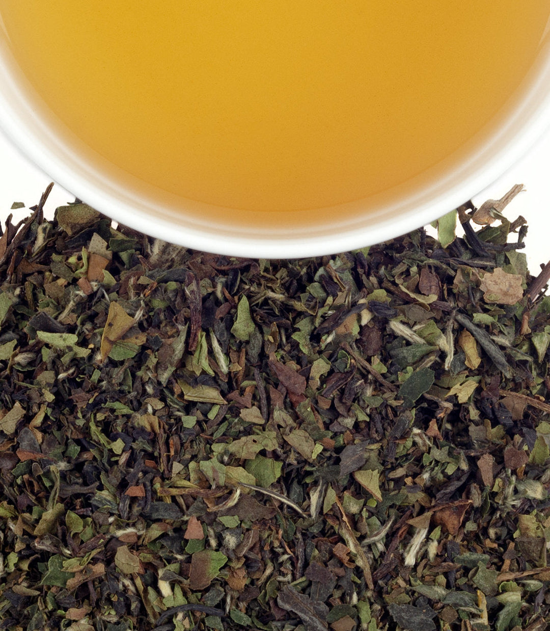 Tea leaves with a cup of tea in the background