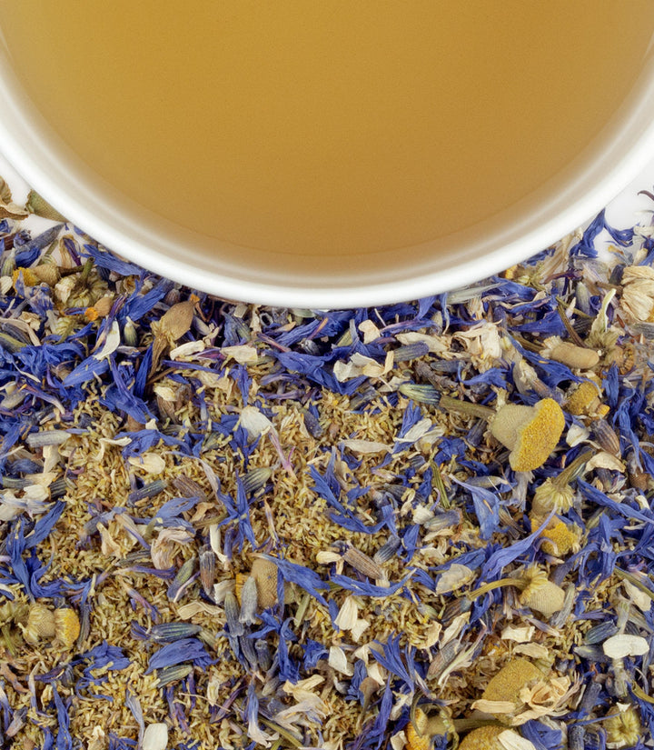 Close-up of dried herbs and a cup of tea with a blurred background.