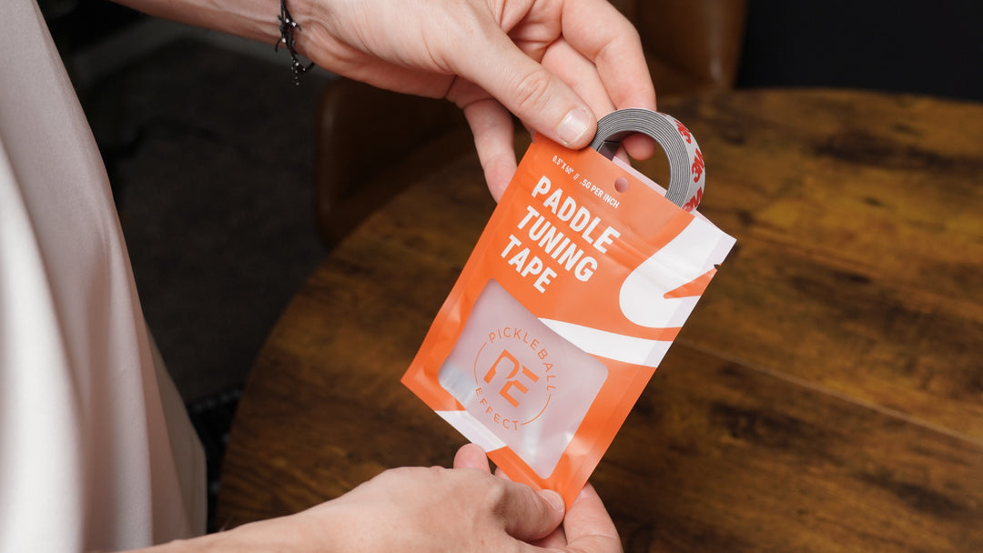 Person holding a package of paddle tuning tape with a wooden surface in the background.