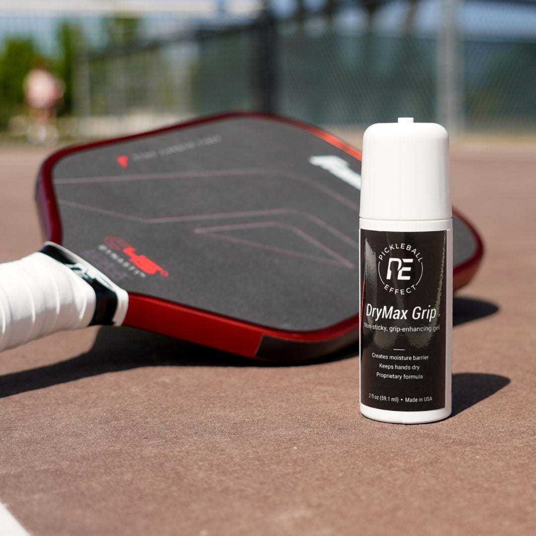 DryMax Grip spray bottle on a pickleball court with a paddle in the background.
