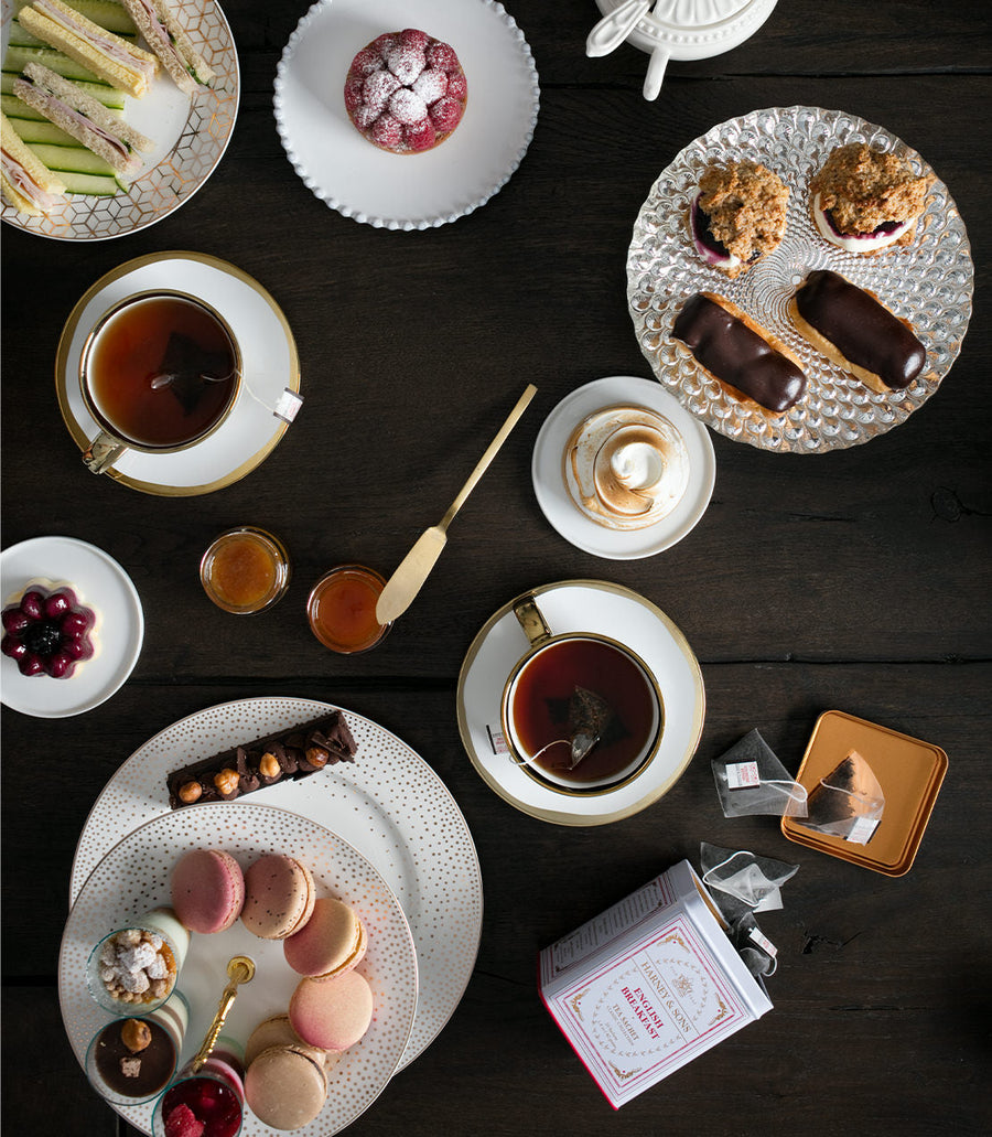 Tea time setting with tea cups, pastries, and tea bags on a wooden table.