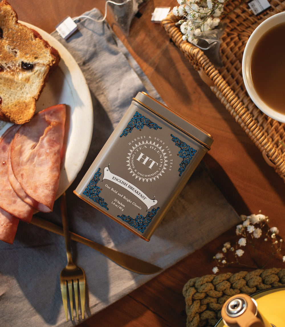 Breakfast setting with toast, bacon, and a tea box on a wooden table.