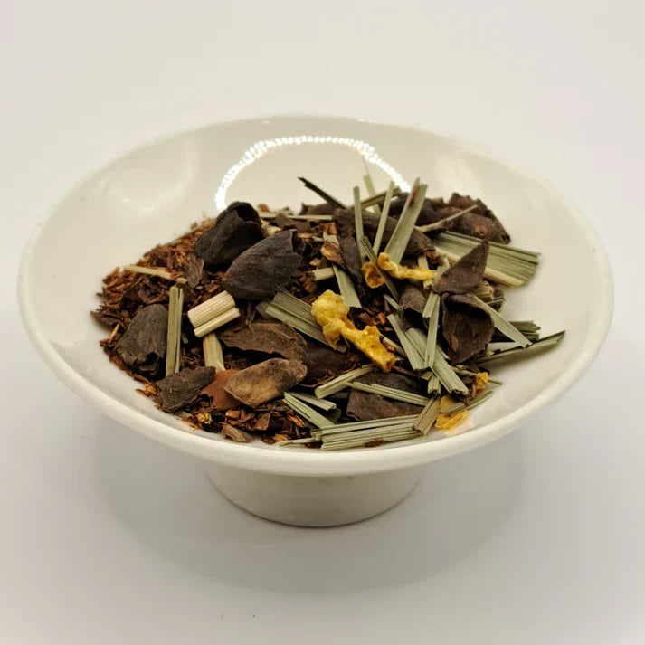 White bowl filled with a mix of dried tea herbs on a white background