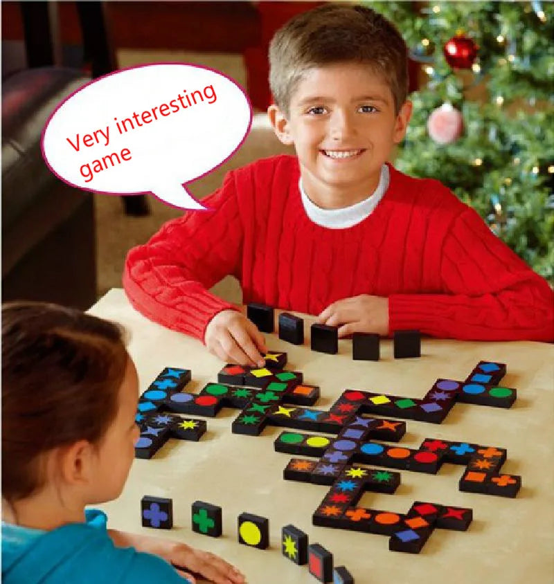 Two children playing a board game with colorful tiles in front of a Christmas tree.