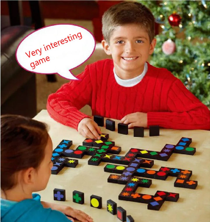 Two children playing a board game with colorful tiles in front of a Christmas tree.