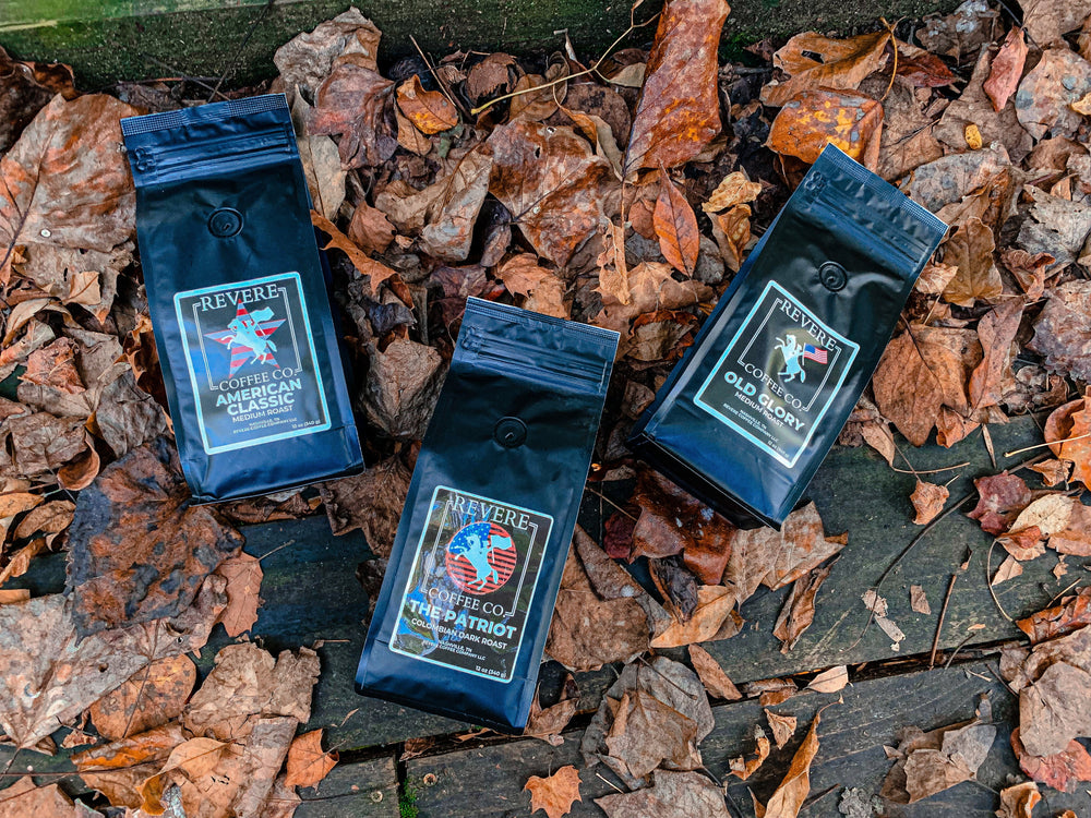 Three packages of coffee on a bed of autumn leaves.