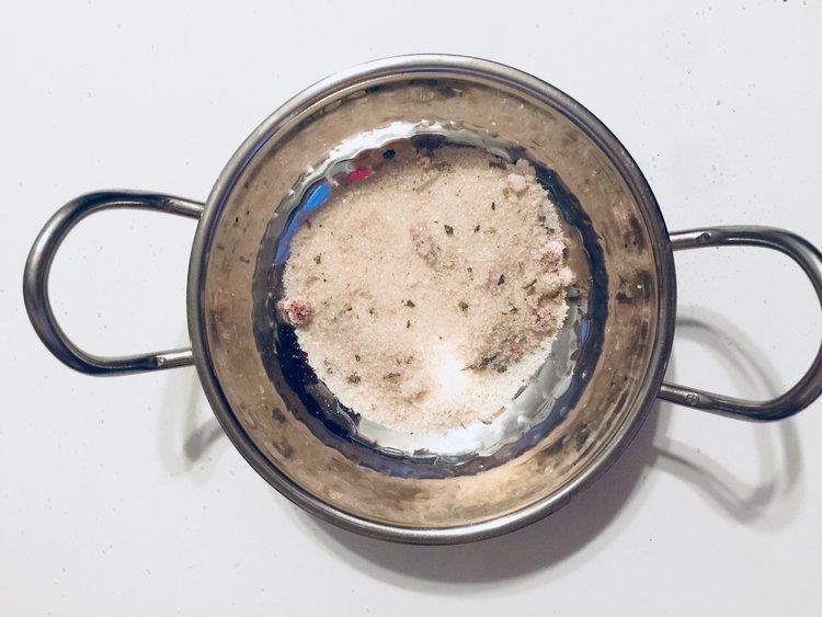 Stainless steel pot with a sugar substance inside on a white background.