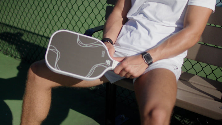 Person holding a pickleball paddle on a court.