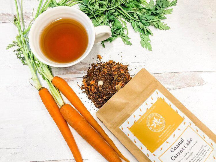 Tea with carrots and a package of tea leaves on a wooden surface.