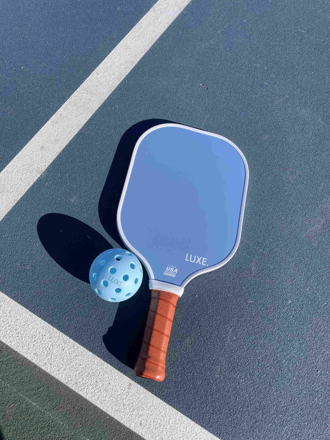 Blue pickleball paddle with brown handle on a court.
