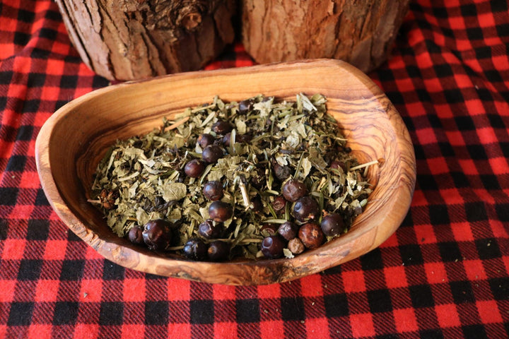 Wooden bowl with dried herbs and berries on a red and black checkered fabric