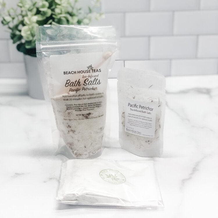 Two packages of Beach House Teas bath salts on a white surface with a blurred background.
