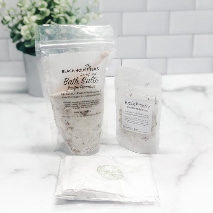 Two packages of Beach House Teas bath salts on a white surface with a blurred background.