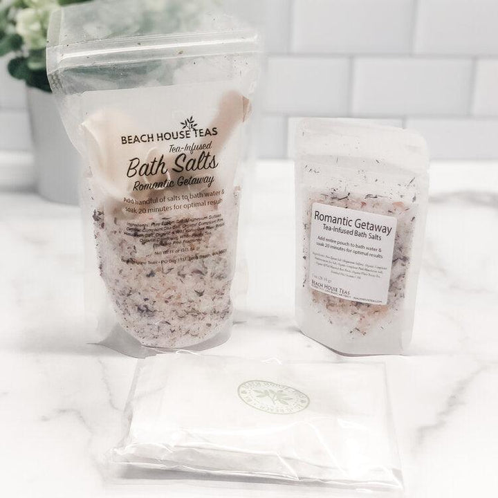 Two bags of Beach House Teas bath salts on a white surface with a blurred background.