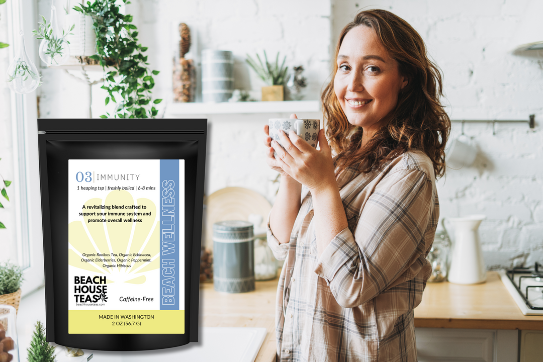Woman holding a mug in a kitchen with a framed product label on the counter.