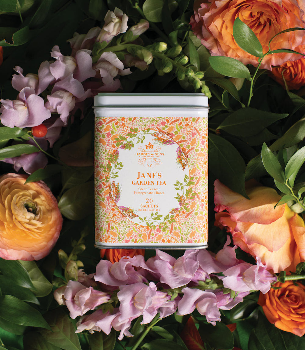Tea canister labeled Jane's Garden Tea surrounded by flowers.