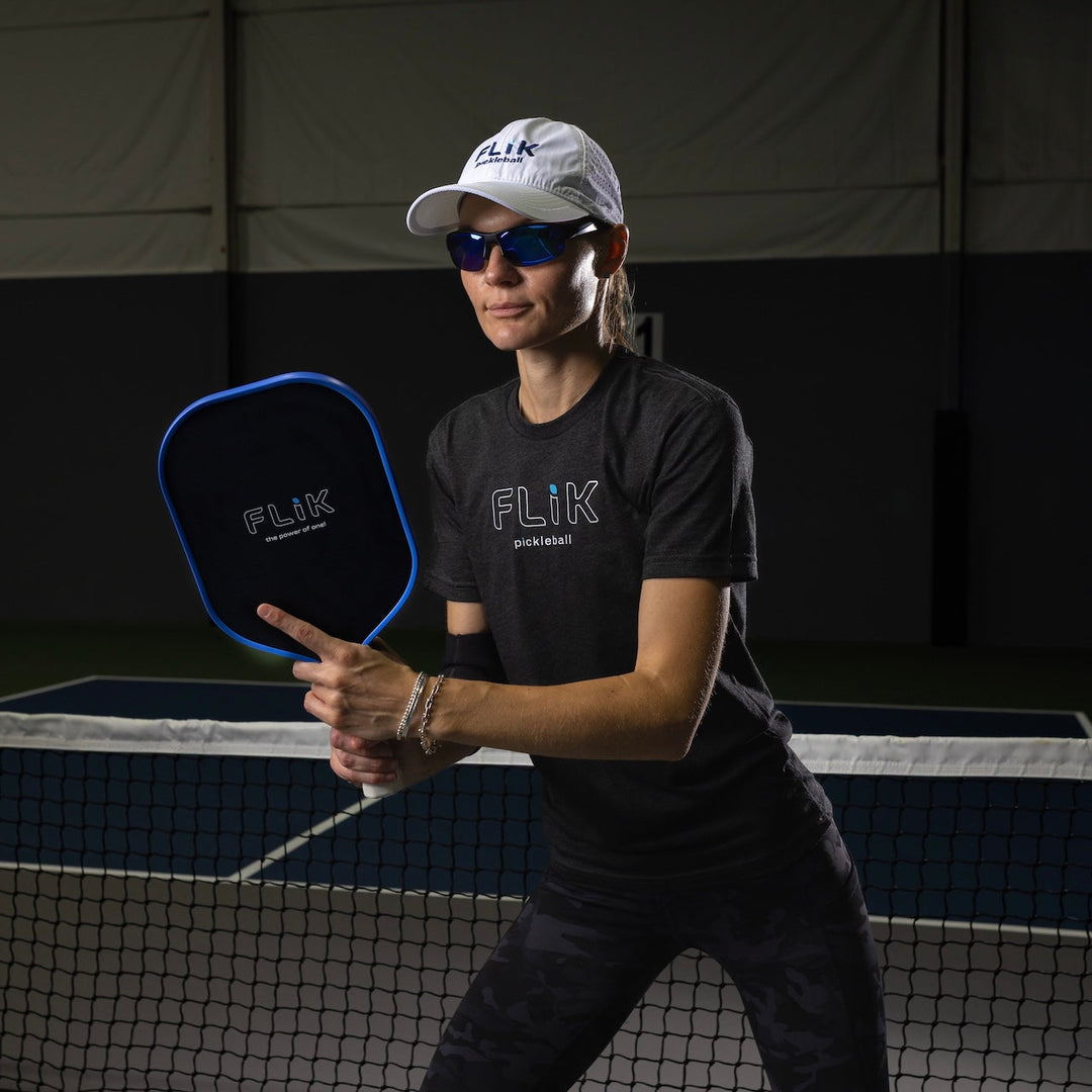 Person holding a pickleball paddle on a court with FLIK branding.