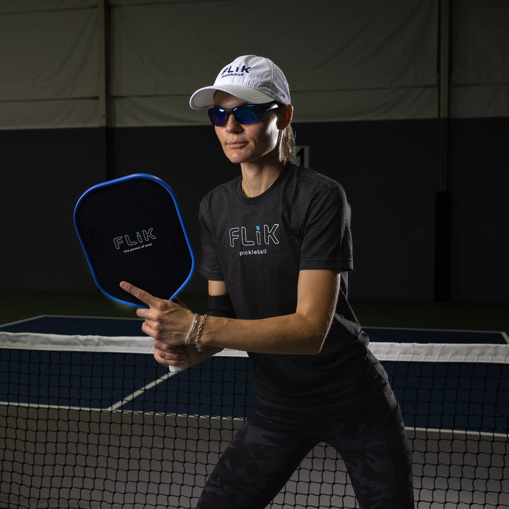 Person holding a pickleball paddle on a court with FLIK branding.