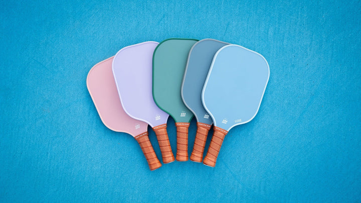 Five paddle sports paddles in various pastel colors on a blue background